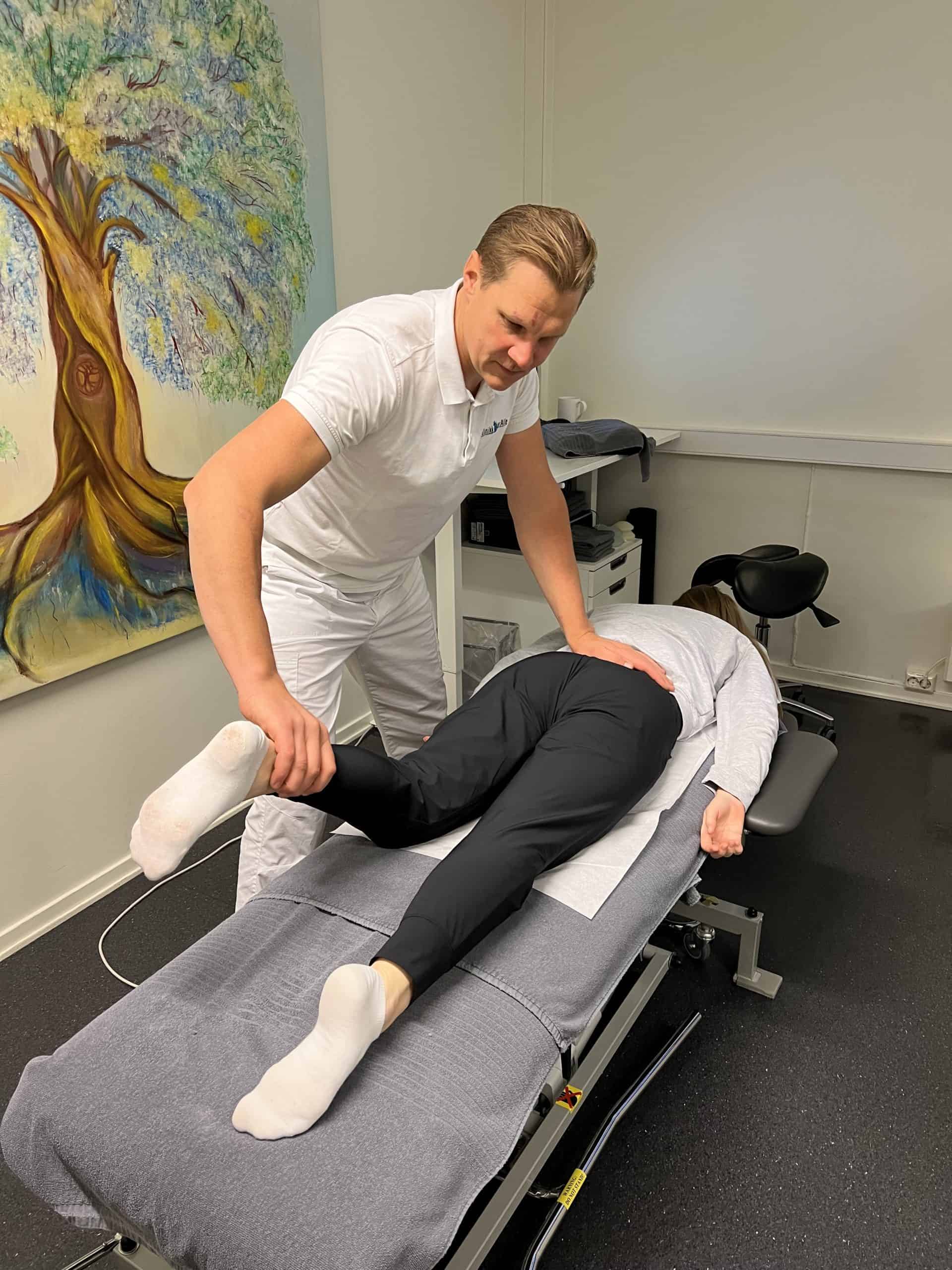 Kiropraktor som undersøker pasient på behandlingsbenk i klinikk.