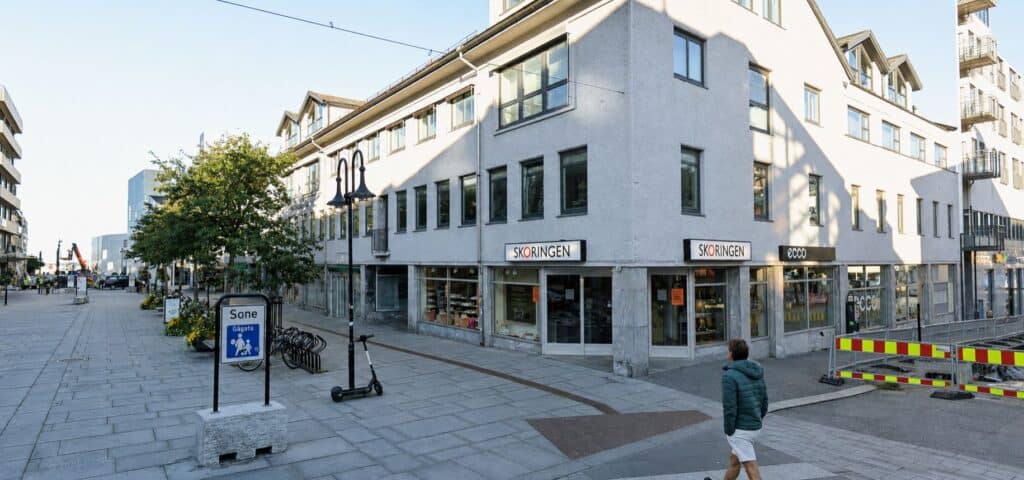 Moderne hjørnebygg med butikker og fortau i sentrum.