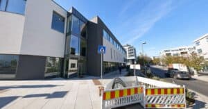 Moderne klinikkbygning med store vinduer og tydelig adkomst, under klar blå himmel.