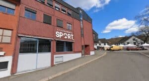 Lillehammer Sport byggning med parkeringsplass og blå himmel.
