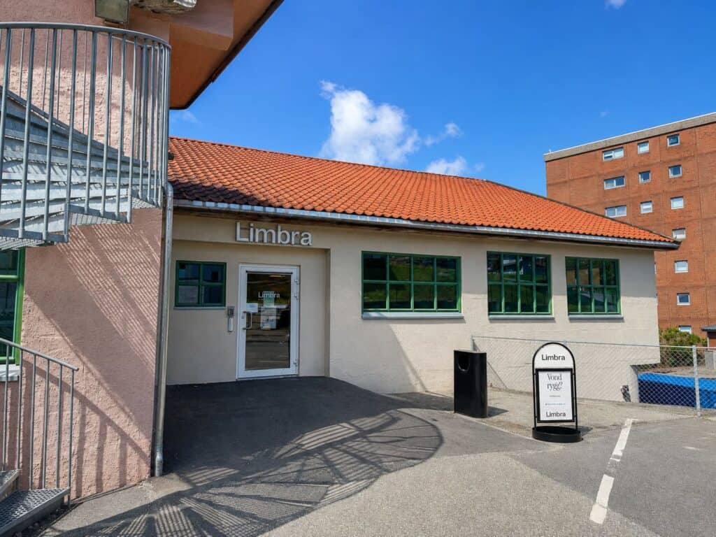 Utendørs bilde av Limbra klinikk med inngang og skilt, klar for pasientbesøk.