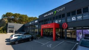 Utvendig bilde av Sørlands TUNET med parkeringsplass og butikkfasade.