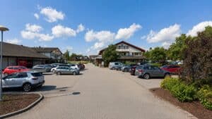 Parkeringsplass foran Limbra klinikk med biler og bygninger under blå himmel.