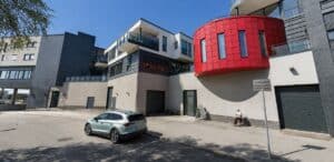 Moderne bygård med parkering og sitteplass foran, i urbant område.