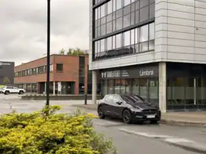 Moderne klinikkbygg med parkering foran, Limba skilt synlig.
