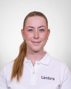 Kvinne i hvit Limbra-polo smilende mot kamera.