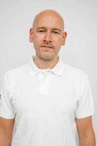 Mann i hvit polo skjorte med nøytral bakgrunn, portrettbilde.