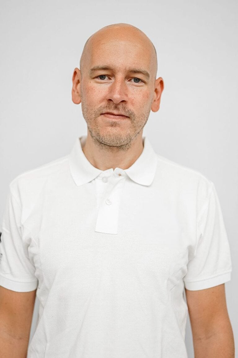 Mann i hvit polo skjorte med nøytral bakgrunn, portrettbilde.