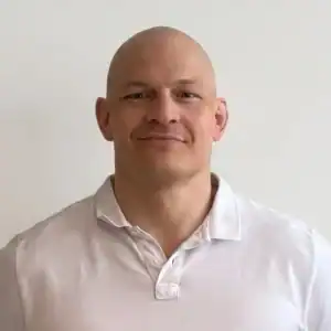 Portrett av Andreas Moss i hvit skjorte mot lys bakgrunn.
