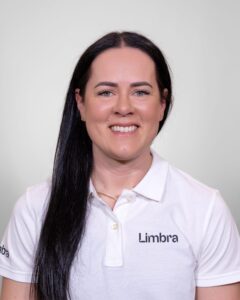 Limbra kiropraktor smilende kvinne i hvit polo med Limbra-logo.
