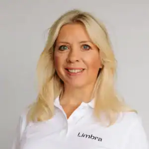 Kvinne med blondt hår i hvit Limbraklær smiler til kameraet.