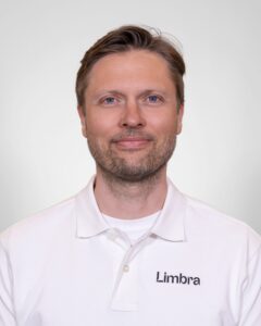 Kiropraktor fra Limbra smilende i hvit klinikkuniform.