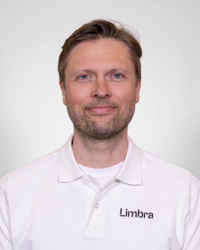 Kiropraktor fra Limbra smilende i hvit klinikkuniform.
