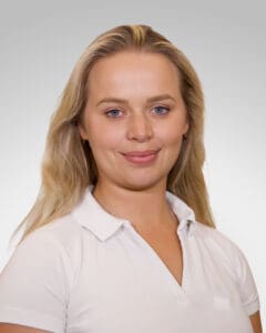 Kvinne med hvit polo smilende mot kamera, portrett.