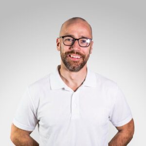 Eirik Holm-Nilsen smilende mann med briller i hvit skjorte.