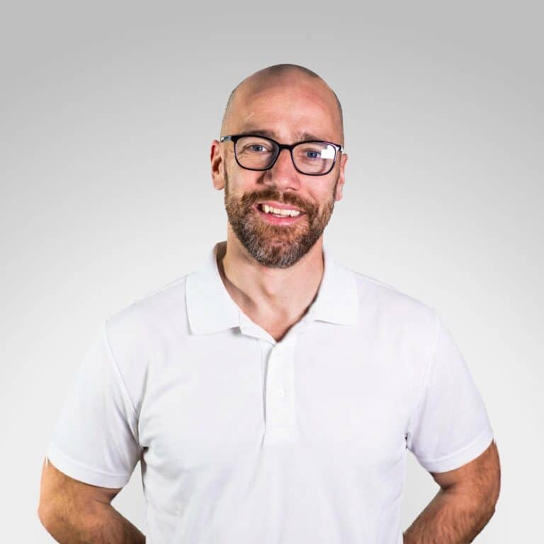 Eirik Holm-Nilsen smilende mann med briller i hvit skjorte.