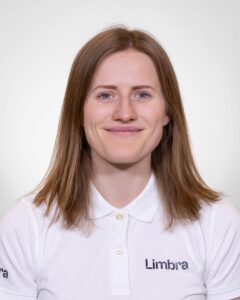 Kvinne i hvit Limba-uniform smilende mot kamera.