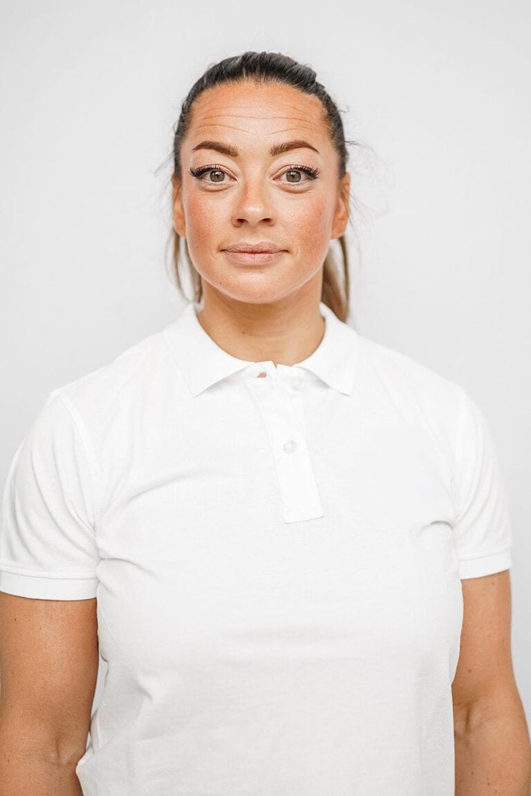 Kvinne med hvit polo-shirt ser direkte inn i kameraet.