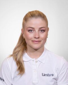 Kvinne i hvit Limba-uniform smilende mot kamera.