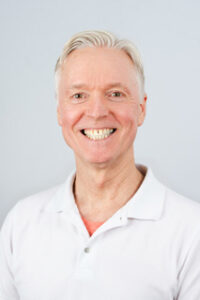 Portrett av Erik Øiangen med hvitt hår og hvit skjorte.