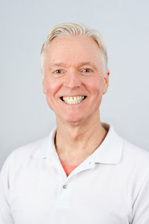 Portrett av Erik Øiangen med hvitt hår og hvit skjorte.