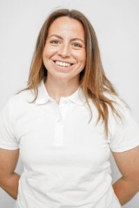 Smilende kvinne i hvit polo-shirt, portrett, nærbilde.
