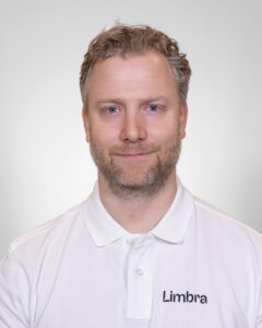 Kiropraktor fra Limbra smilende mot kamera, hvit bakgrunn.