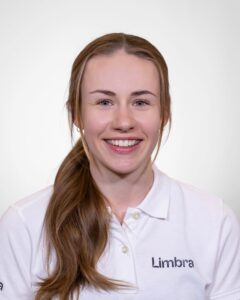 Smilende kvinne i Limbra-polo, portrett mot hvit bakgrunn.