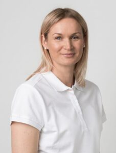 Kvinne i hvit uniform smilende mot kamera, portrett.