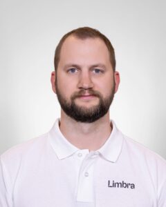 Kiropraktor fra Limbra med hvit polo, nøytral bakgrunn.