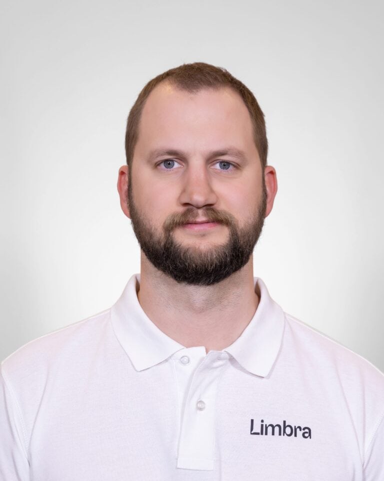 Kiropraktor fra Limbra med hvit polo, nøytral bakgrunn.