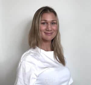 Julianne Skansen smilende kvinne med blondt hår i hvit t-skjorte.