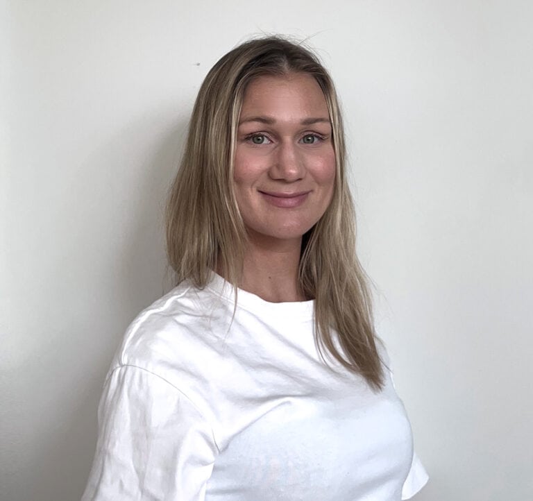 Julianne Skansen smilende kvinne med blondt hår i hvit t-skjorte.