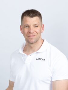 Kenneth Bergflødt, kiropraktor ved Limbra, smilende i hvit polo.