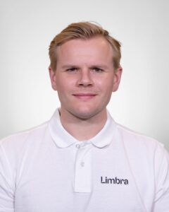 Kiropraktor fra Limbra smilende i hvit polo med Limbra-logo.