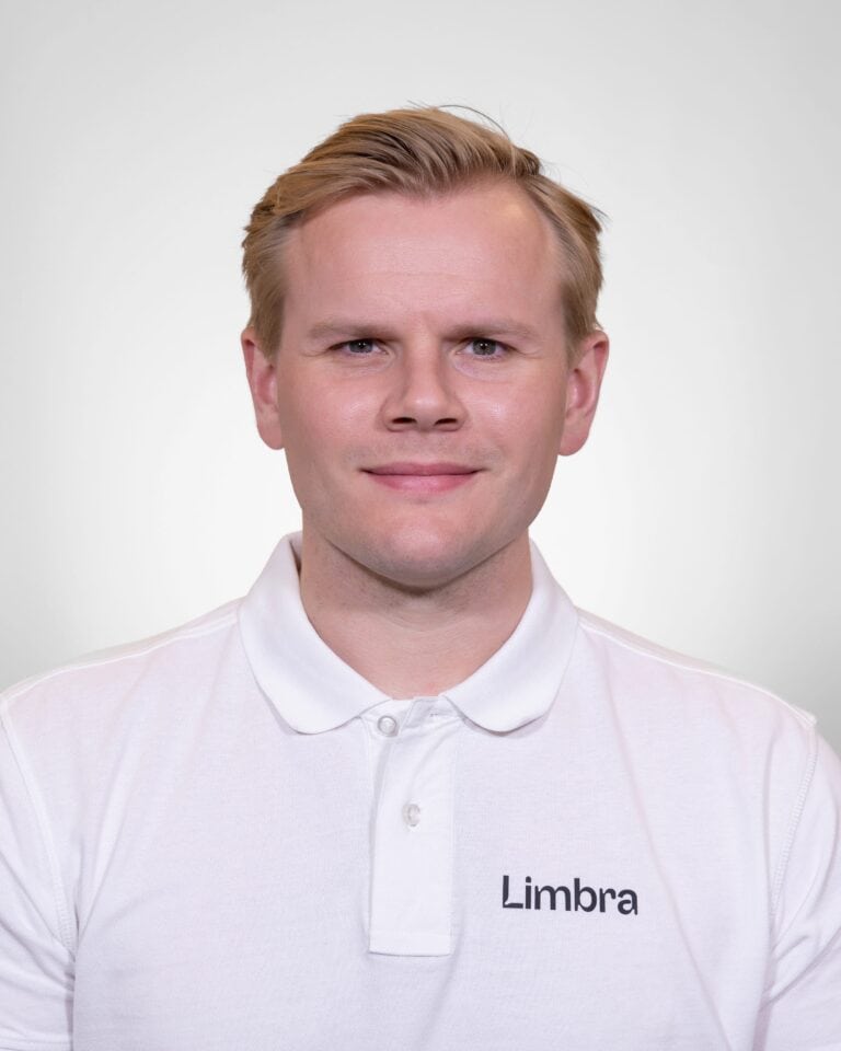 Kiropraktor fra Limbra smilende i hvit polo med Limbra-logo.