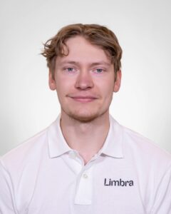 Ung mann i hvit Limba-polo smiler mot kamera.