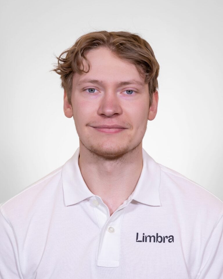 Ung mann i hvit Limba-polo smiler mot kamera.