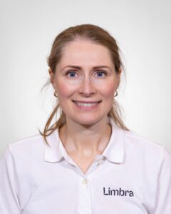 Kvinne i hvit Limba-uniform smiler mot kamera.