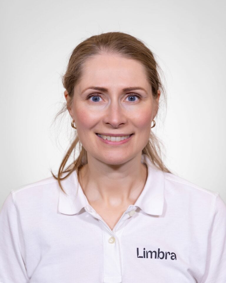 Kvinne i hvit Limba-uniform smiler mot kamera.