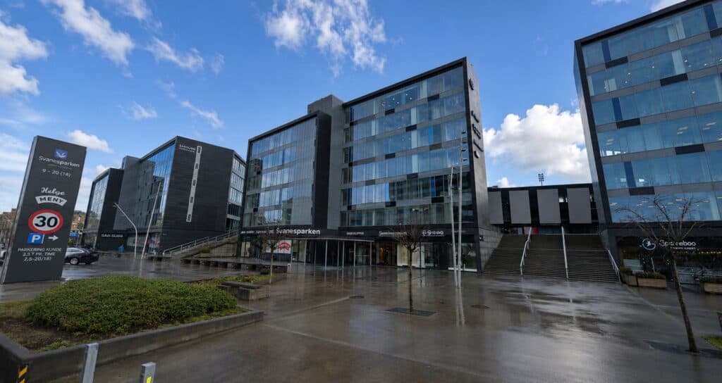 Moderne kontorbygg i sentrum med glassfasade og parkeringsmuligheter.