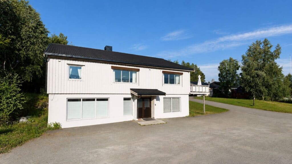 Moderne to-etasjes klinikkbygning med store vinduer og grønt landskap.