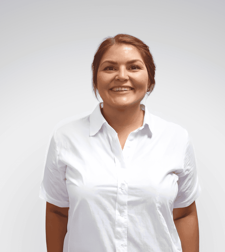 Kvinne smilende helsepersonell i hvit skjorte mot lys bakgrunn.
