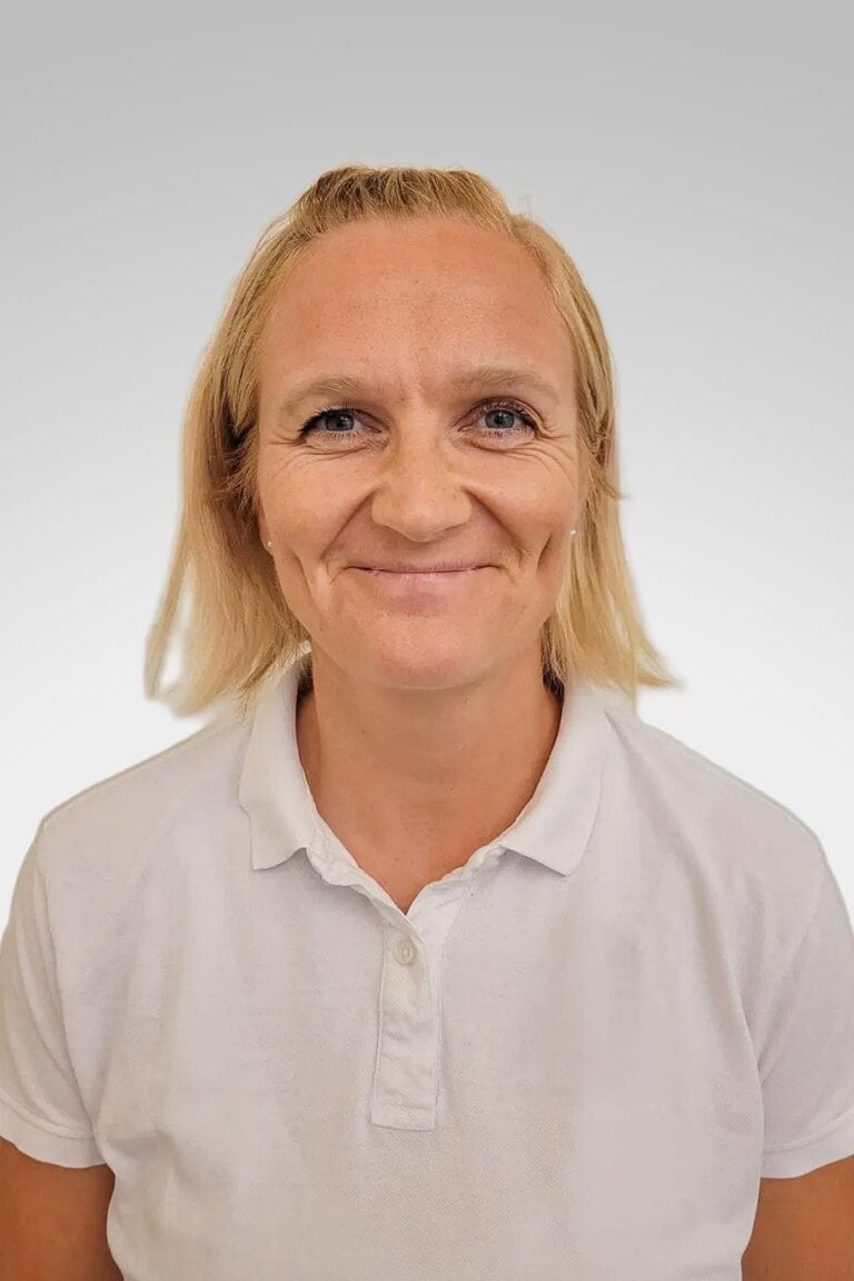 Kvinne smilende terapeut i hvit skjorte, nærbilde.
