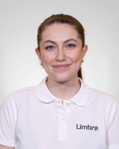 Kvinne i hvit Limba-uniform smilende mot kamera.