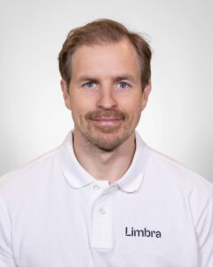 Kiropraktor fra Limbra smilende i hvit polo med Limbra-logo.