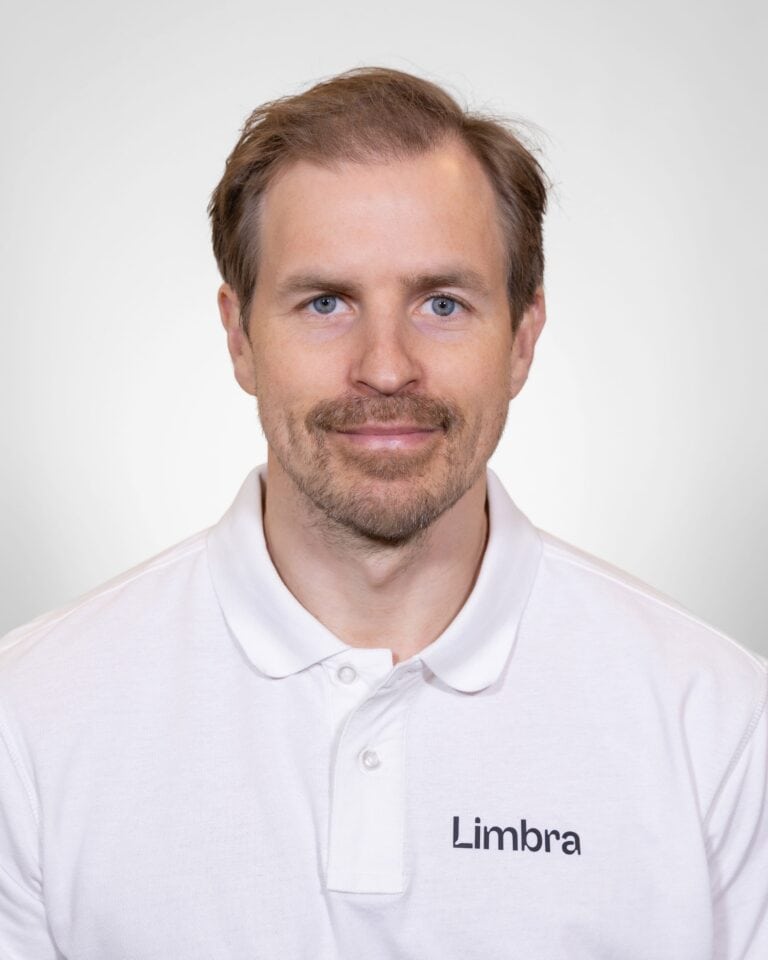 Kiropraktor fra Limbra smilende i hvit polo med Limbra-logo.