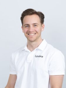 Limbra kiropraktor smilende mann i hvit polo med Limbra-logo.