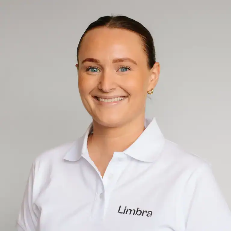 Marthine Solheim smiler i hvit klinikkuniform med Limba-logo.