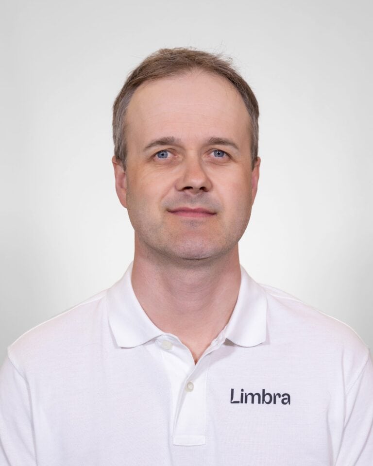 Kiropraktor i hvit skjorte med Limbra-logo, nærbilde.